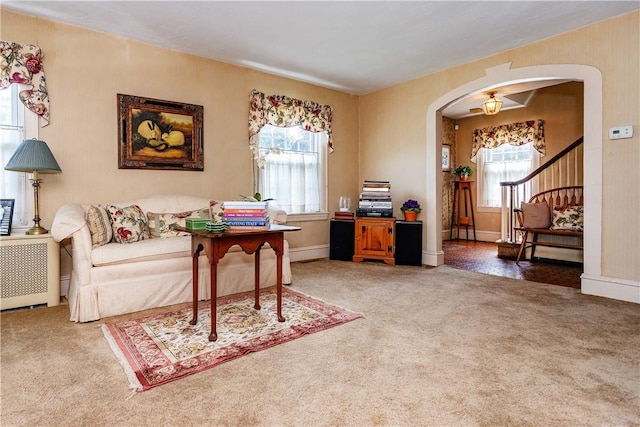 64 Riverfarm Rd, Cranston, RI 02910 - carpeted living area featuring healthy amount of natural light, arched walkways, radiator heating unit, and stairs