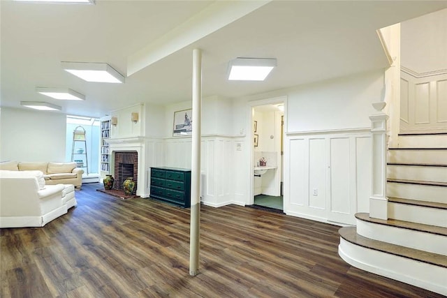 29 Orchard Ave, Providence, RI 02906 - living room featuring stairway, dark wood-type flooring, a brick fireplace, a wainscoted wall, and a decorative wall