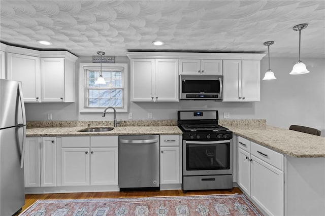 160 Coburn St, Warwick, RI 02889 - kitchen with stainless steel appliances, a peninsula, white cabinetry, hanging light fixtures, and wood finished floors