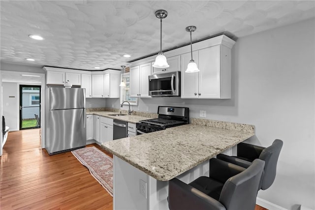 160 Coburn St, Warwick, RI 02889 - kitchen featuring appliances with stainless steel finishes, light wood-style flooring, a peninsula, white cabinetry, and recessed lighting
