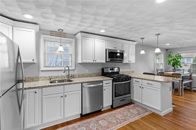 160 Coburn St, Warwick, RI 02889 - kitchen with appliances with stainless steel finishes, a peninsula, white cabinets, recessed lighting, and light wood-type flooring