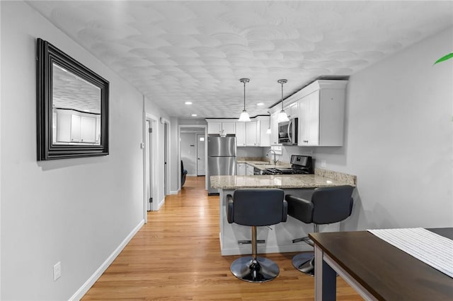 160 Coburn St, Warwick, RI 02889 - kitchen with stainless steel appliances, a peninsula, white cabinetry, light wood-style flooring, and recessed lighting