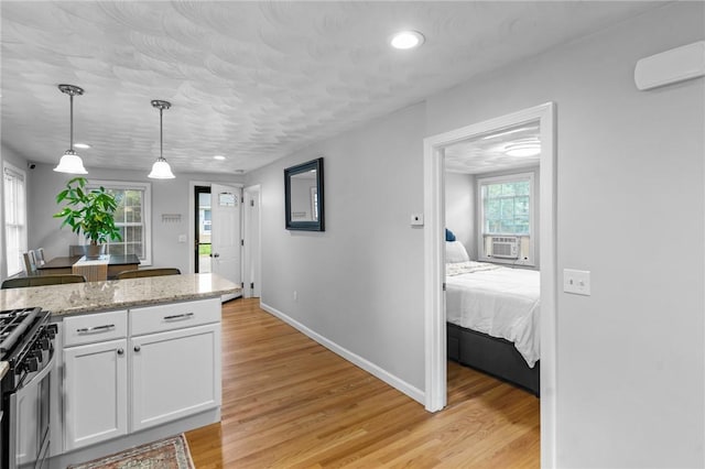 160 Coburn St, Warwick, RI 02889 - kitchen with stainless steel range with gas stovetop, white cabinets, light wood-style floors, decorative light fixtures, and recessed lighting