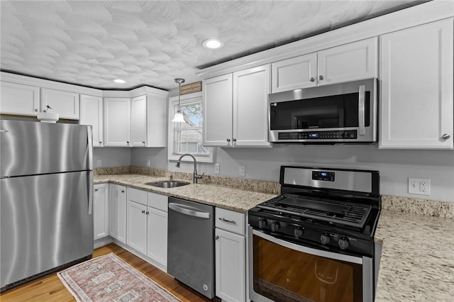 160 Coburn St, Warwick, RI 02889 - kitchen featuring appliances with stainless steel finishes, white cabinetry, light wood-style floors, recessed lighting, and light stone counters