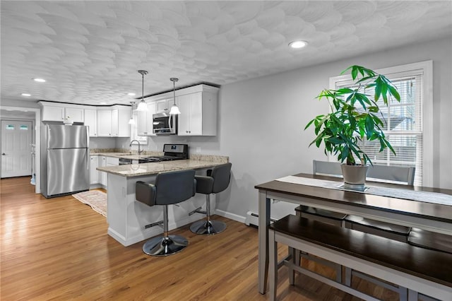 160 Coburn St, Warwick, RI 02889 - kitchen with stainless steel appliances, a peninsula, white cabinets, light wood-style flooring, and recessed lighting