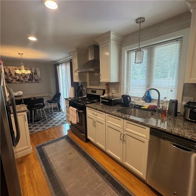 34 Ridge St, East Providence, RI 02914 - kitchen featuring appliances with stainless steel finishes, wall chimney range hood, wood finished floors, white cabinetry, and recessed lighting