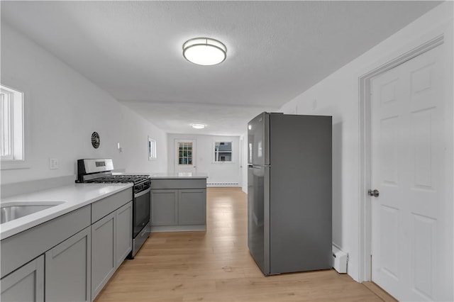 15 Maplewood Ave, Warwick, RI 02889 - kitchen with stainless steel appliances, gray cabinets, light wood-type flooring, a baseboard heating unit, and light countertops