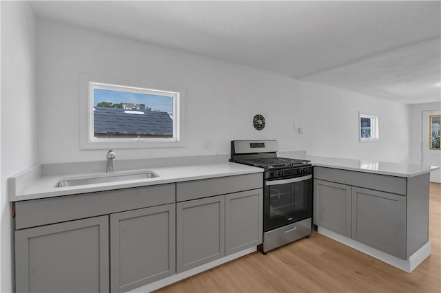 15 Maplewood Ave, Warwick, RI 02889 - kitchen with stainless steel gas stove, gray cabinetry, light wood-type flooring, a peninsula, and healthy amount of natural light