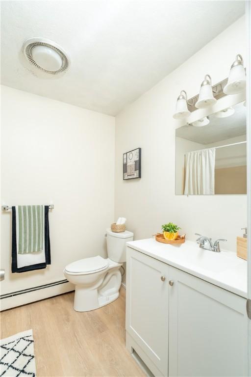 10 E St Unit 207, Cranston, RI 02920 - full bath featuring a baseboard heating unit, wood finished floors, vanity, and curtained shower