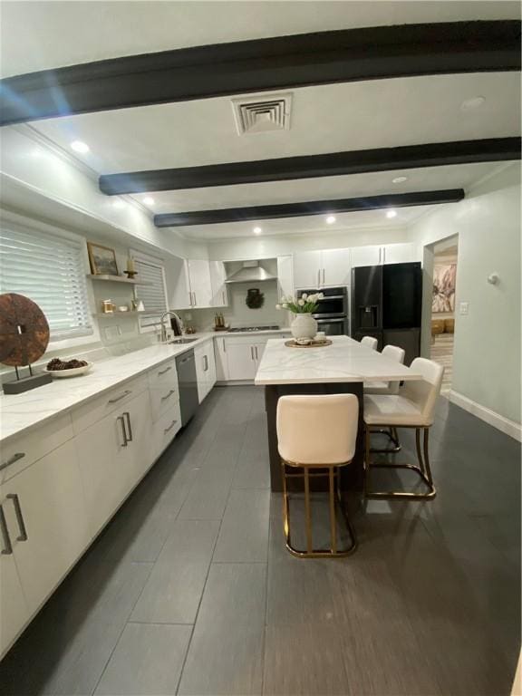 109 Cobble Hill Rd, Lincoln, RI 02865 - kitchen with black fridge, stainless steel dishwasher, white cabinetry, beam ceiling, and wall chimney exhaust hood