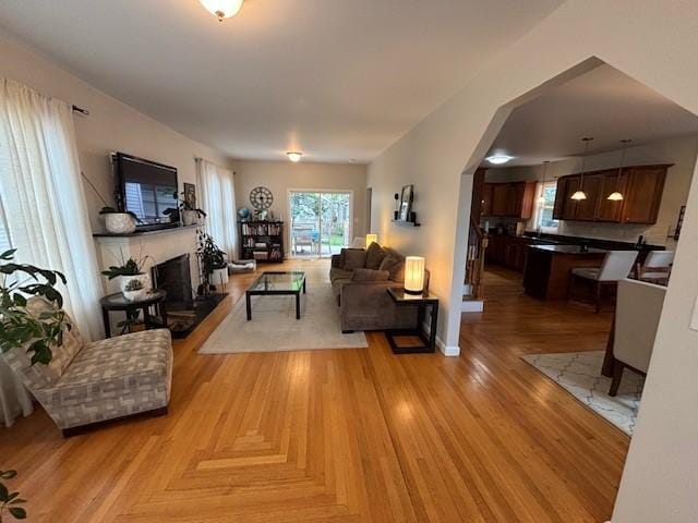 75 Lauriston St, Providence, RI 02906 - living area with arched walkways, a fireplace with raised hearth, and light wood-style floors