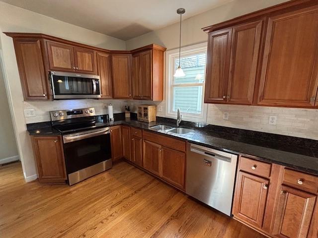 75 Lauriston St, Providence, RI 02906 - kitchen featuring appliances with stainless steel finishes, brown cabinetry, light wood-style flooring, and decorative light fixtures