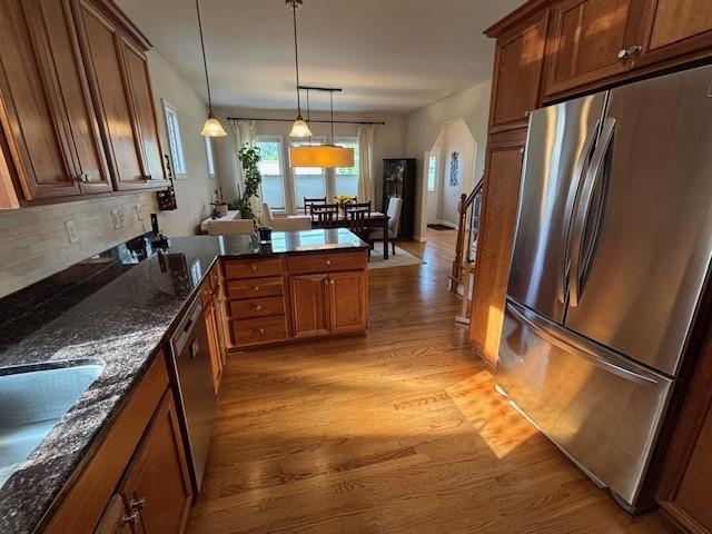 75 Lauriston St, Providence, RI 02906 - kitchen with appliances with stainless steel finishes, light wood-style floors, brown cabinetry, pendant lighting, and a peninsula