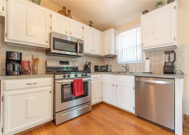 14 Gateway Ct, Warwick, RI 02889 - kitchen with appliances with stainless steel finishes, light wood-style flooring, white cabinets, tasteful backsplash, and light countertops