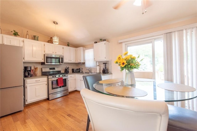 14 Gateway Ct, Warwick, RI 02889 - kitchen with stainless steel appliances, white cabinetry, light wood finished floors, tasteful backsplash, and vaulted ceiling