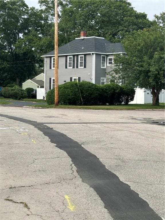 6 Larkspur Rd, Warwick, RI 02886 - view of property exterior with roof with shingles, a chimney, and view of wooded area