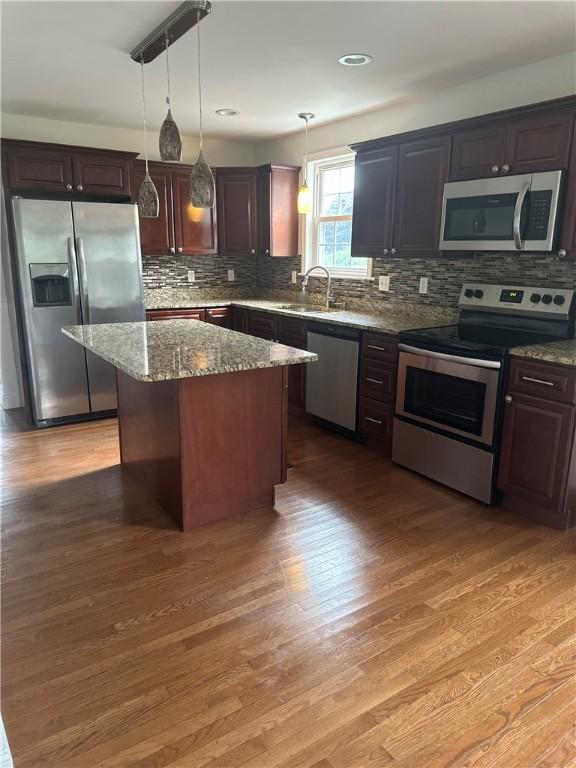 6 Larkspur Rd, Warwick, RI 02886 - kitchen with appliances with stainless steel finishes, light wood-style flooring, stone counters, backsplash, and decorative light fixtures