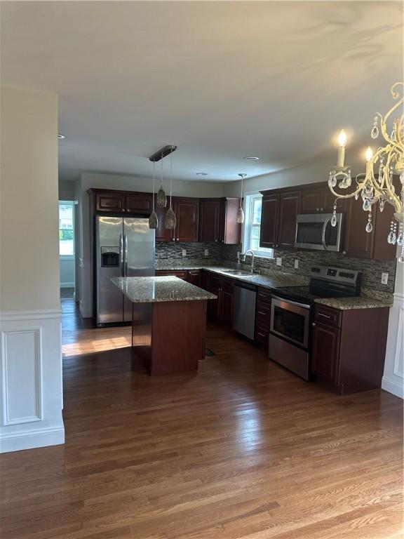 6 Larkspur Rd, Warwick, RI 02886 - kitchen with appliances with stainless steel finishes, dark brown cabinetry, backsplash, a center island, and a wainscoted wall