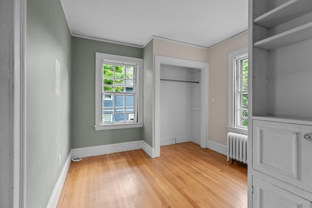 189 Butler Ave, Providence, RI 02906 - unfurnished bedroom featuring radiator heating unit, light wood-type flooring, ornamental molding, and a closet