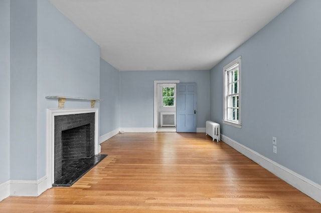 189 Butler Ave, Providence, RI 02906 - unfurnished living room with radiator heating unit, light wood-style floors, and a fireplace
