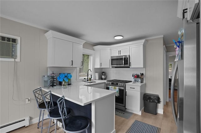 12 Elmore Ave, North Providence, RI 02911 - kitchen with appliances with stainless steel finishes, baseboard heating, light wood-style flooring, white cabinets, and a decorative wall