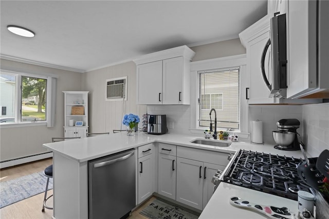 12 Elmore Ave, North Providence, RI 02911 - kitchen featuring appliances with stainless steel finishes, a peninsula, backsplash, an AC wall unit, and light countertops