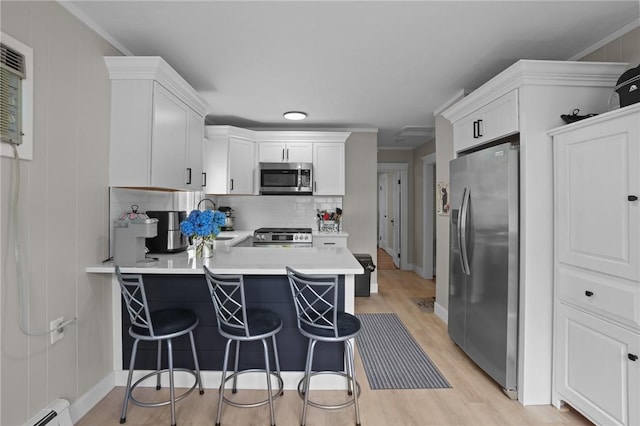 12 Elmore Ave, North Providence, RI 02911 - kitchen featuring appliances with stainless steel finishes, baseboard heating, light wood-style floors, a peninsula, and tasteful backsplash
