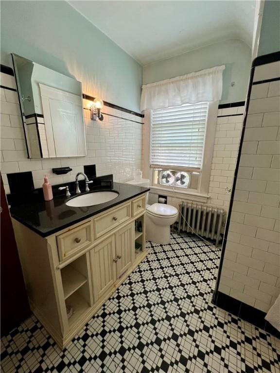 55 Greylock Ave, Cranston, RI 02910 - bathroom with radiator heating unit, tile patterned floors, tile walls, and vanity