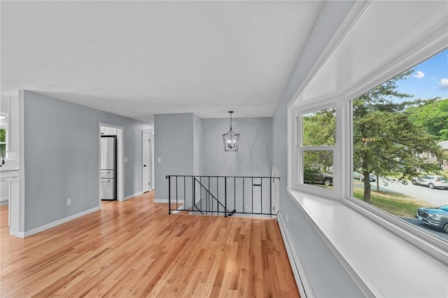 7 Antony Ave, Bristol, RI 02809 - empty room featuring a baseboard heating unit, light wood-style flooring, and a chandelier