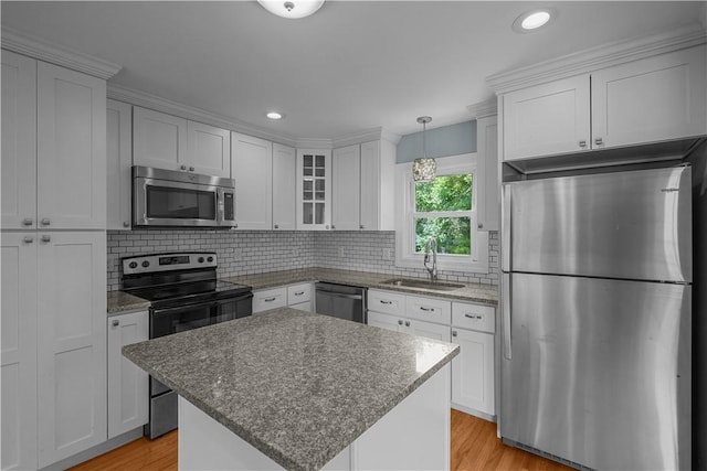 14 Gladding St, Bristol, RI 02809 - kitchen with stainless steel appliances, light wood-style flooring, white cabinetry, decorative backsplash, and glass insert cabinets