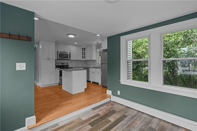 14 Gladding St, Bristol, RI 02809 - kitchen with appliances with stainless steel finishes, a baseboard radiator, glass insert cabinets, a kitchen island, and decorative backsplash