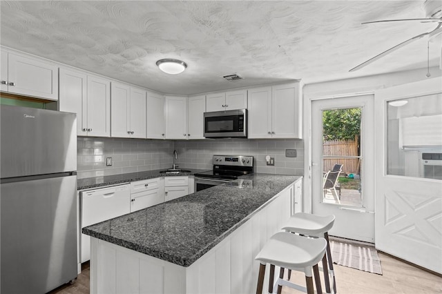 190 White Ave, Warwick, RI 02889 - kitchen with stainless steel appliances, white cabinetry, backsplash, and dark stone counters
