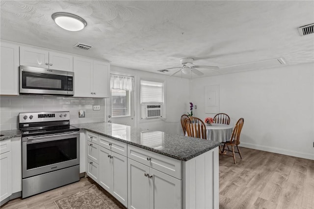 190 White Ave, Warwick, RI 02889 - kitchen featuring stainless steel appliances, a peninsula, white cabinetry, light wood finished floors, and dark stone counters