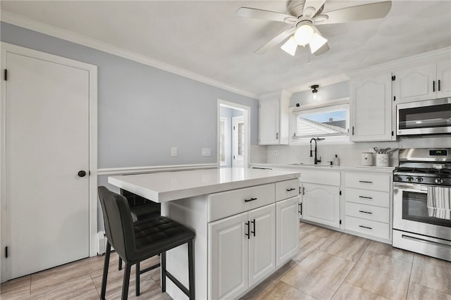 62 Bristol Ave, Pawtucket, RI 02861 - kitchen featuring stainless steel appliances, a center island, light countertops, a ceiling fan, and white cabinets
