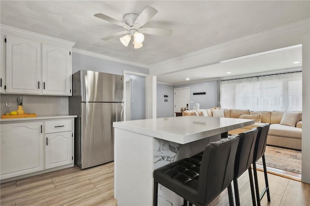 62 Bristol Ave, Pawtucket, RI 02861 - kitchen featuring freestanding refrigerator, a kitchen breakfast bar, white cabinets, ceiling fan, and open floor plan