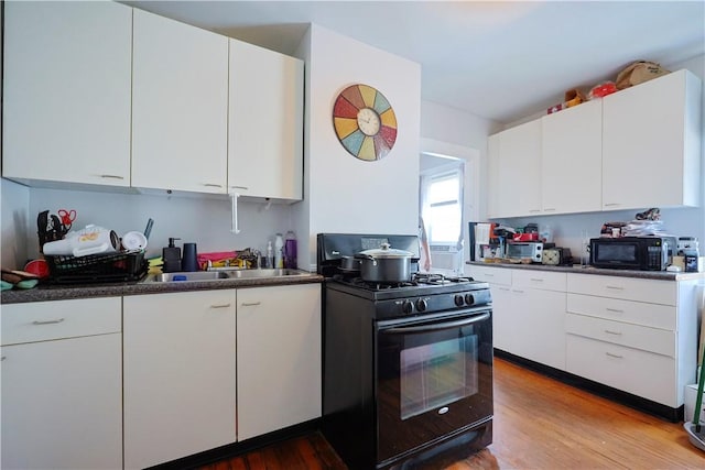10 Walnut St, East Providence, RI 02914 - kitchen featuring black appliances, dark countertops, light wood-style flooring, white cabinetry, and modern cabinets