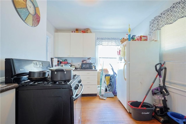 10 Walnut St, East Providence, RI 02914 - kitchen featuring black gas range oven, freestanding refrigerator, white cabinetry, and light wood-style flooring