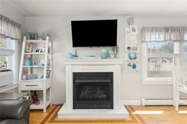 13 Vaughan Ave, Newport, RI 02840 - living room featuring a baseboard heating unit, a fireplace with raised hearth, and wood finished floors