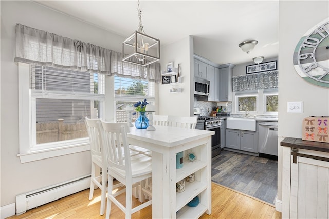 13 Vaughan Ave, Newport, RI 02840 - kitchen featuring appliances with stainless steel finishes, gray cabinetry, a baseboard radiator, a chandelier, and wood finished floors