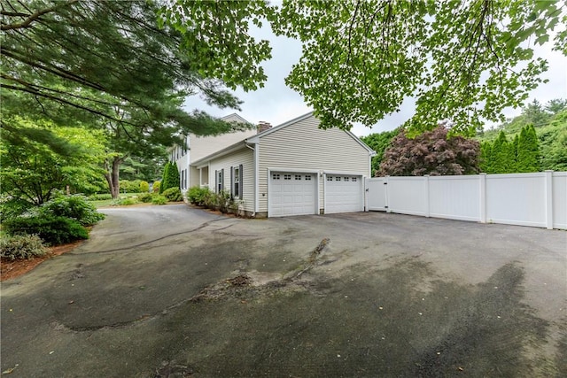 11 Greenbrier Rd, Smithfield, RI 02828 - view of home's exterior featuring driveway, a chimney, and an attached garage