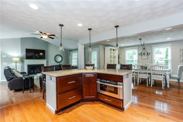 11 Greenbrier Rd, Smithfield, RI 02828 - kitchen with oven, light wood-style floors, a glass covered fireplace, a ceiling fan, and pendant lighting