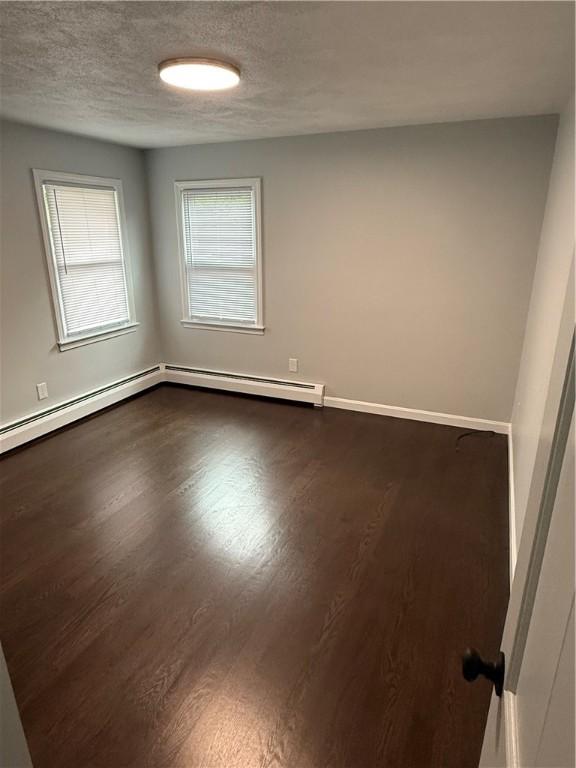 446 Angell Rd, North Providence, RI 02904 - unfurnished room with dark wood-style floors, a textured ceiling, and a baseboard radiator