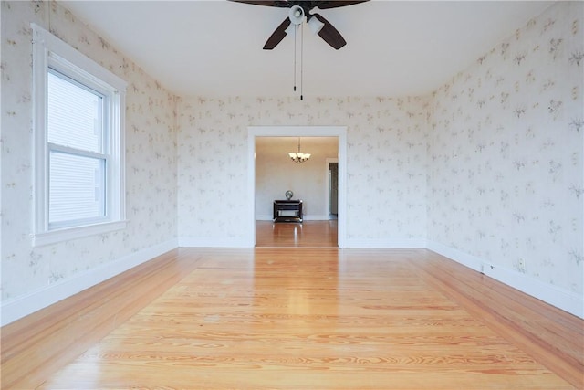 162 Rand St, Central Falls, RI 02863 - empty room with light wood-style flooring, a chandelier, a ceiling fan, and wallpapered walls