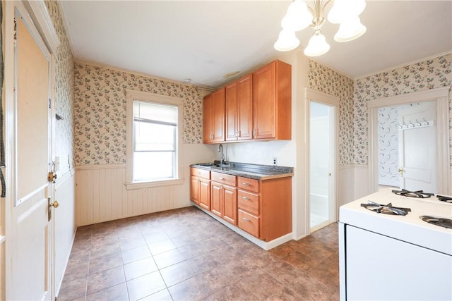 162 Rand St, Central Falls, RI 02863 - kitchen featuring wainscoting, wallpapered walls, a chandelier, white range with gas stovetop, and brown cabinets