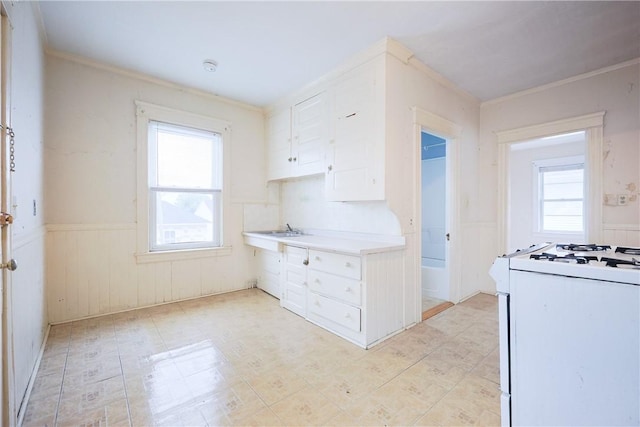 162 Rand St, Central Falls, RI 02863 - kitchen featuring white gas range, wainscoting, white cabinets, light countertops, and crown molding