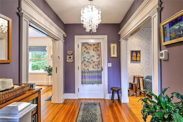 179 Elmgrove Ave, Providence, RI 02906 - foyer entrance with light wood-style floors, a chandelier, and decorative columns