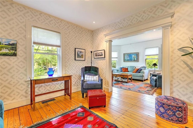 179 Elmgrove Ave, Providence, RI 02906 - living area featuring wallpapered walls, wood-type flooring, healthy amount of natural light, and decorative columns