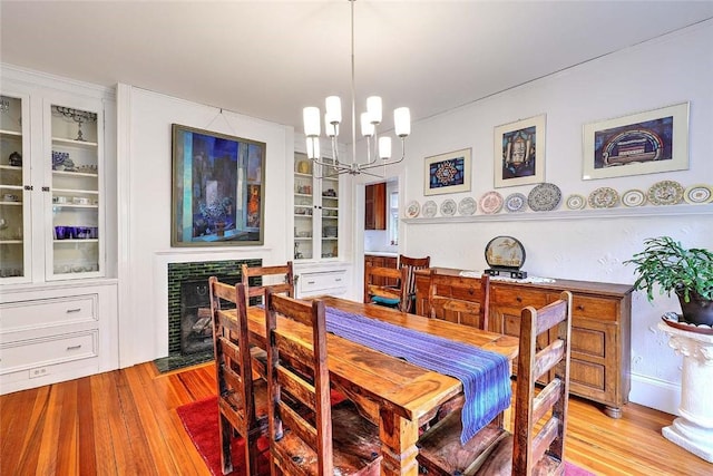 179 Elmgrove Ave, Providence, RI 02906 - dining room with a chandelier, light wood-style flooring, a tile fireplace, and built in shelves