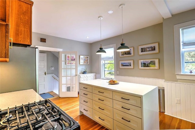 179 Elmgrove Ave, Providence, RI 02906 - kitchen with freestanding refrigerator, wood finished floors, gas range oven, light countertops, and a wainscoted wall