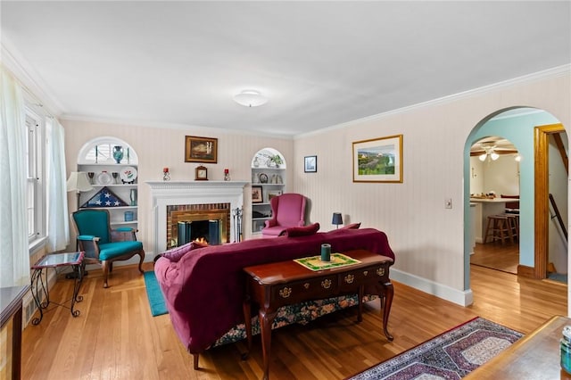 13 Welcome Rd, Smithfield, RI 02917 - living room with arched walkways, light wood-style flooring, ornamental molding, and a brick fireplace